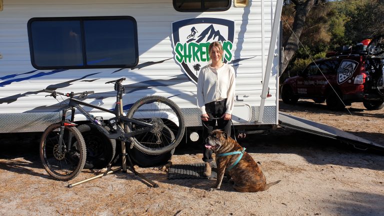A large dog and customer in front of the Shredlys Toy Hauler caravan and 4x4 tour bus - MTB Tasmania